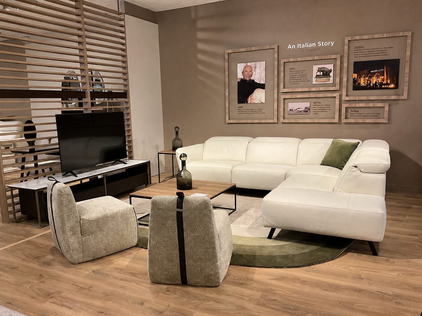 Living-room vignette with a white leather sectional staged in front of the brand's Italian heritage wall.